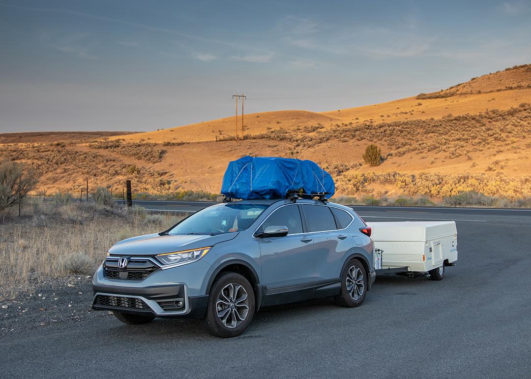 A blue Honda CR-V with a loaded roof rack and is used to pull a pop-up camper for a trip to rural eastern Oregon.