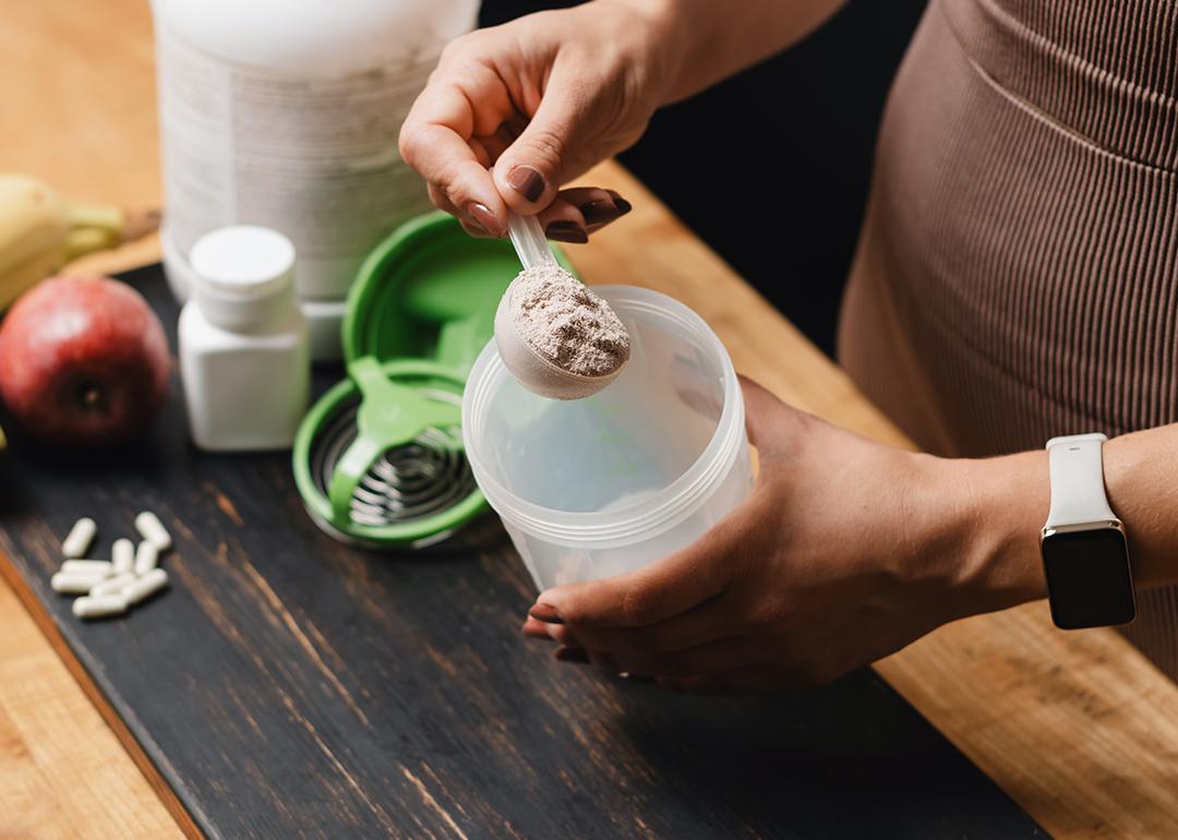 A spoonful of creatine powder being put into a shaker.