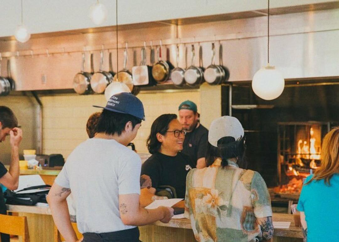 Customers and staff of an open-kitchen restaurant mingle.