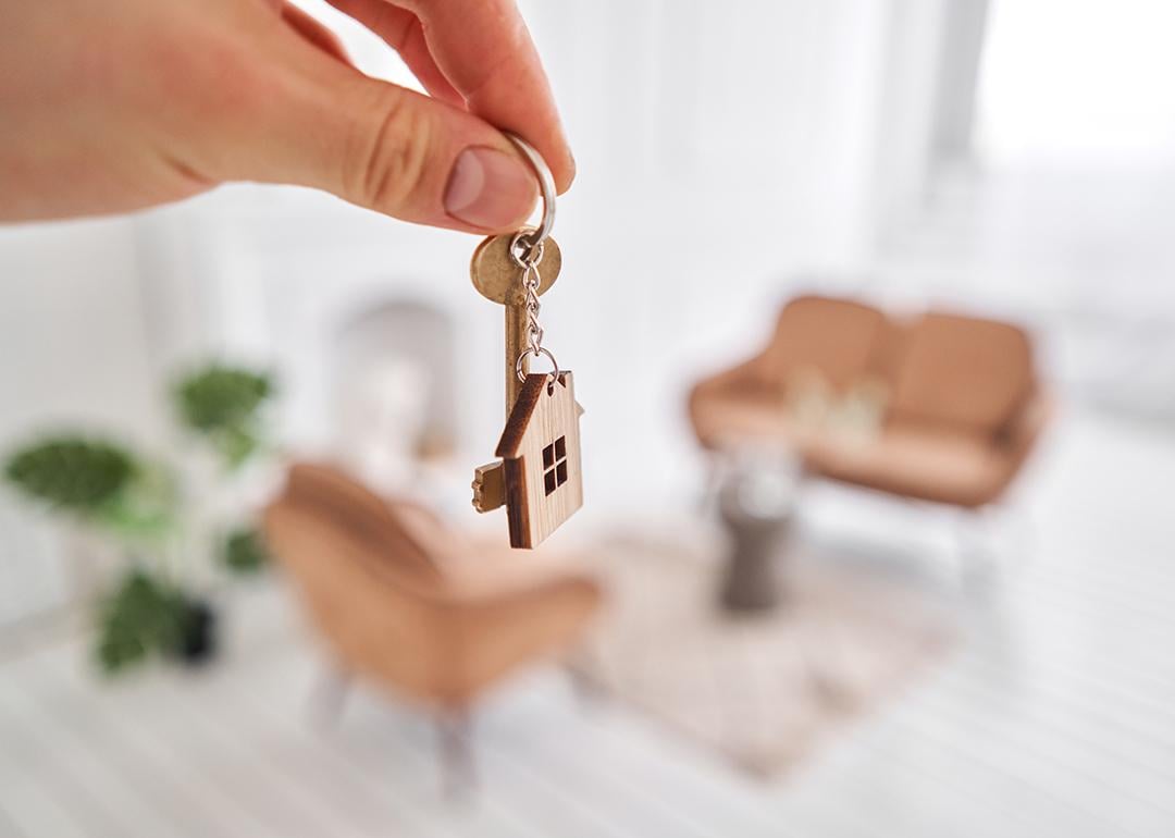 Property owner holds house keys over the backdrop of the home's living area.