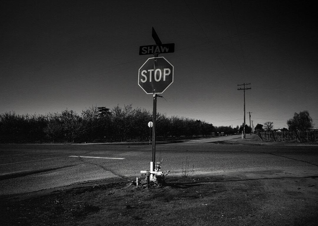 A black and white photo of a stop sign in the middle of an empty intersection.