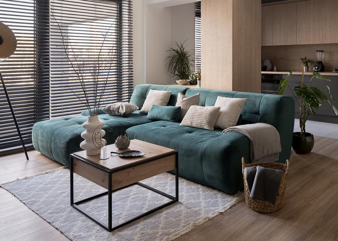 A two-piece blue-green corner sofa set placed in a modern living room.