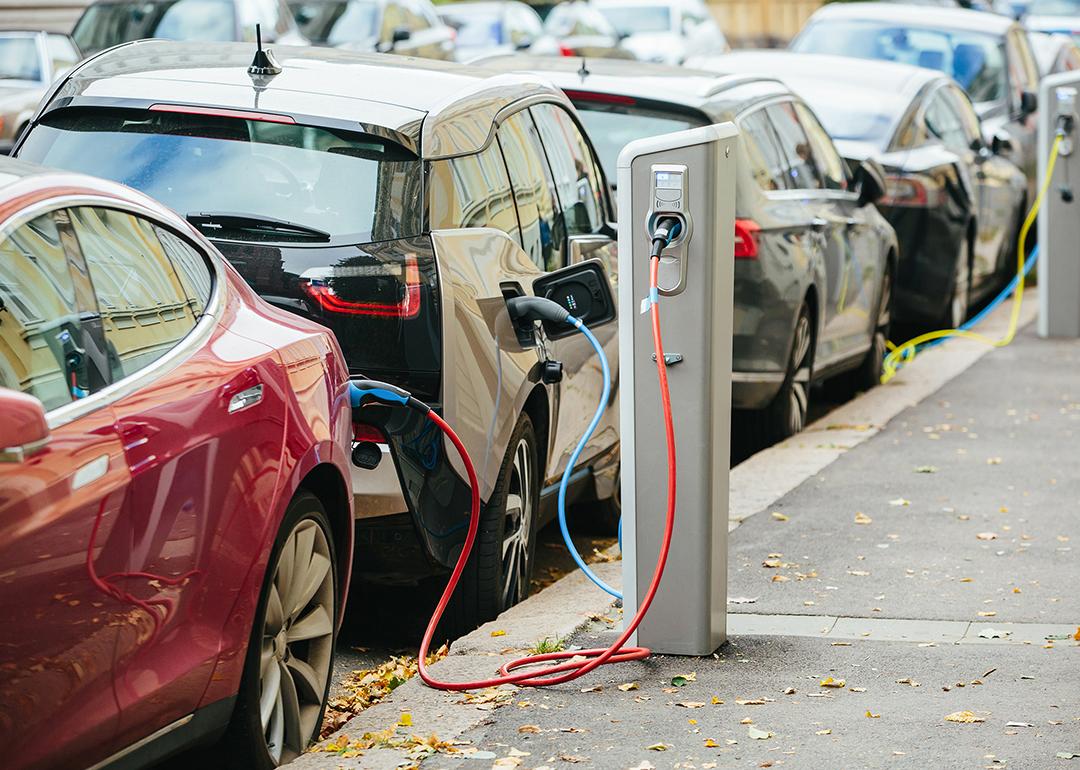 A lane of electric cars being charged on the side of a street.