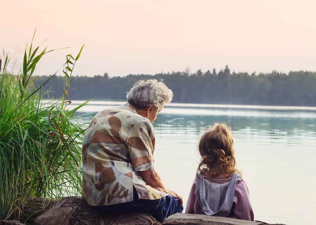 Grandparent sits with grandchild, overlooking the river on a warm day.