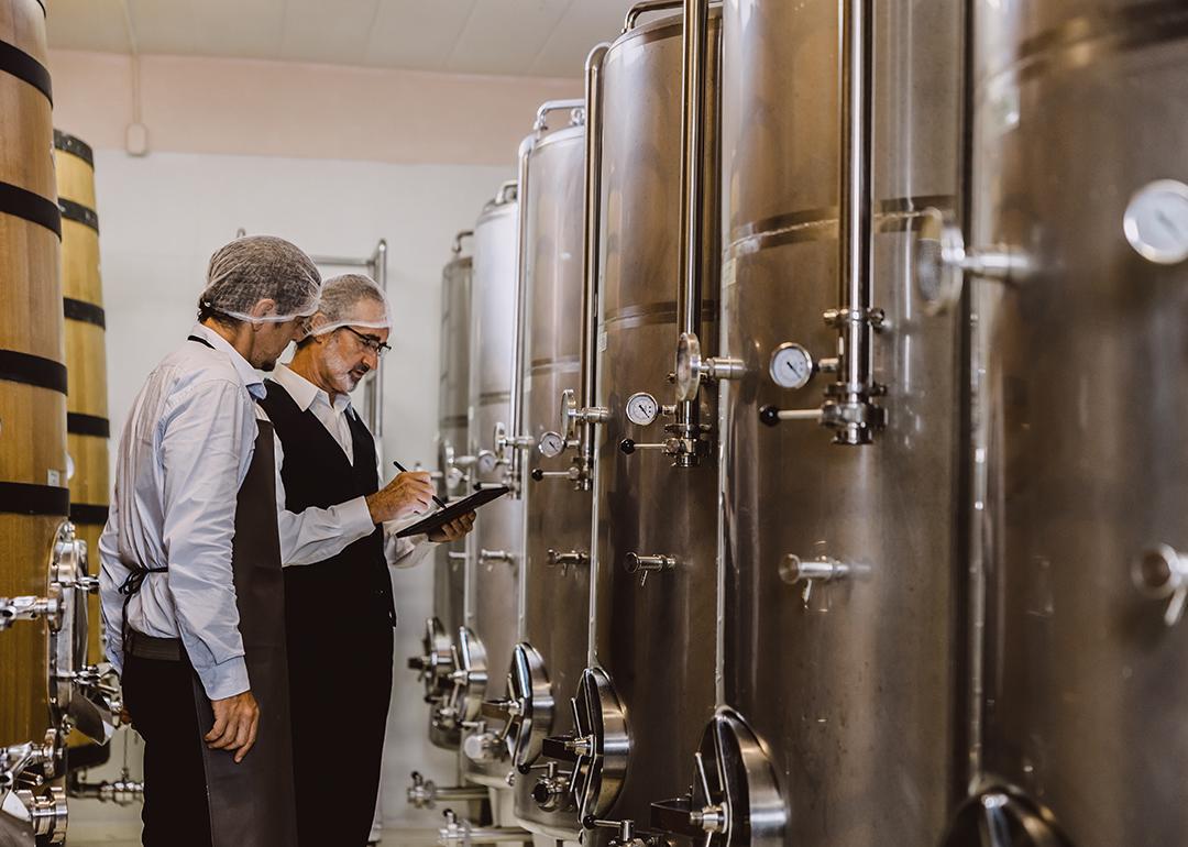 Two winemaking professionals inspecting the large winery storage and equipment.