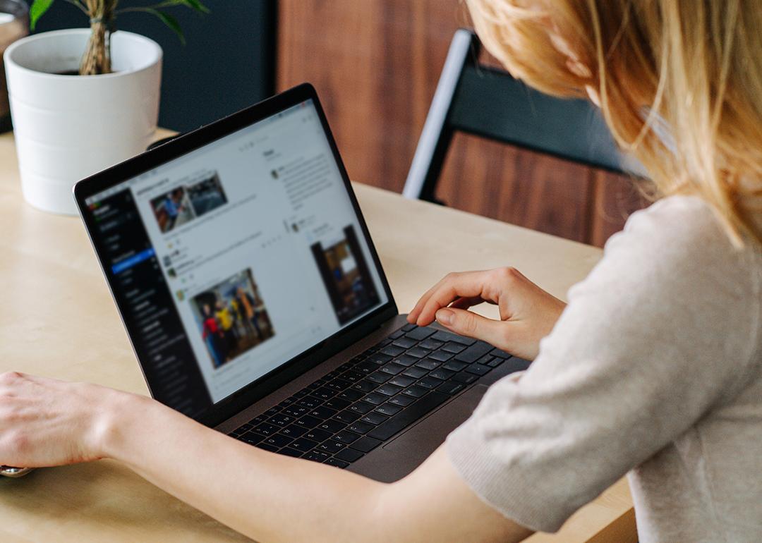 A woman browsing on a laptop looking at the feed of a user on a social media app.