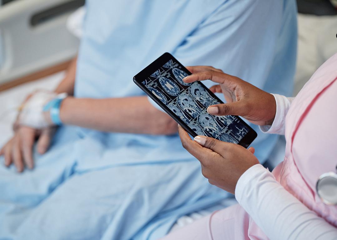 A doctor examines scan results of the head and brain beside a concussion patient.