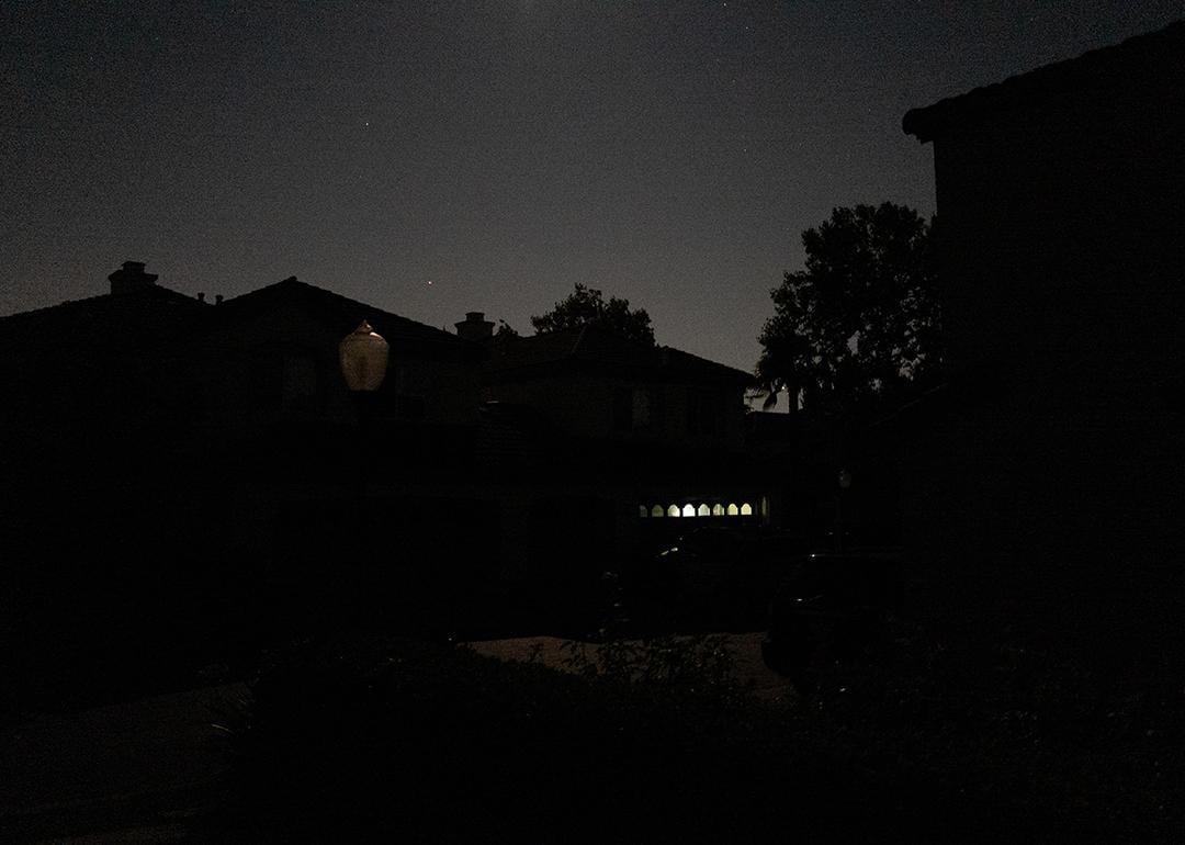 A suburban street in San Ramon, California is entirely dark except for a garage illuminated by a battery powered lantern during the Pacific Gas and Electric Public Safety Power Shutoff in 2019.