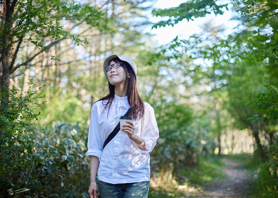 A young woman enjoying the view of the sky during summer in a forest.