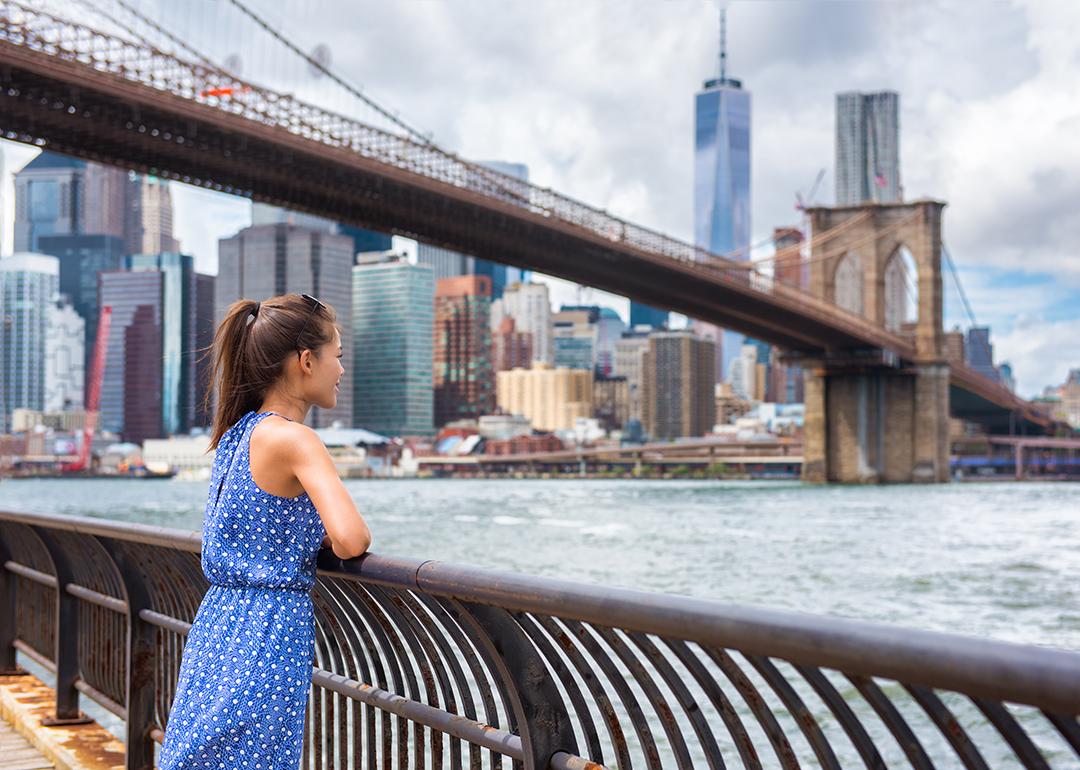 Woman touring NYC enjoying the Manhattan skyline from Brooklyn park.