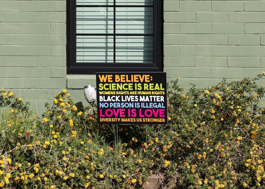 "We believe" yard sign that says, "Science is real, womens rights are human rights, black lives matter, no human is illegal, love is love, diversity makes us stronger” outside of a green home.