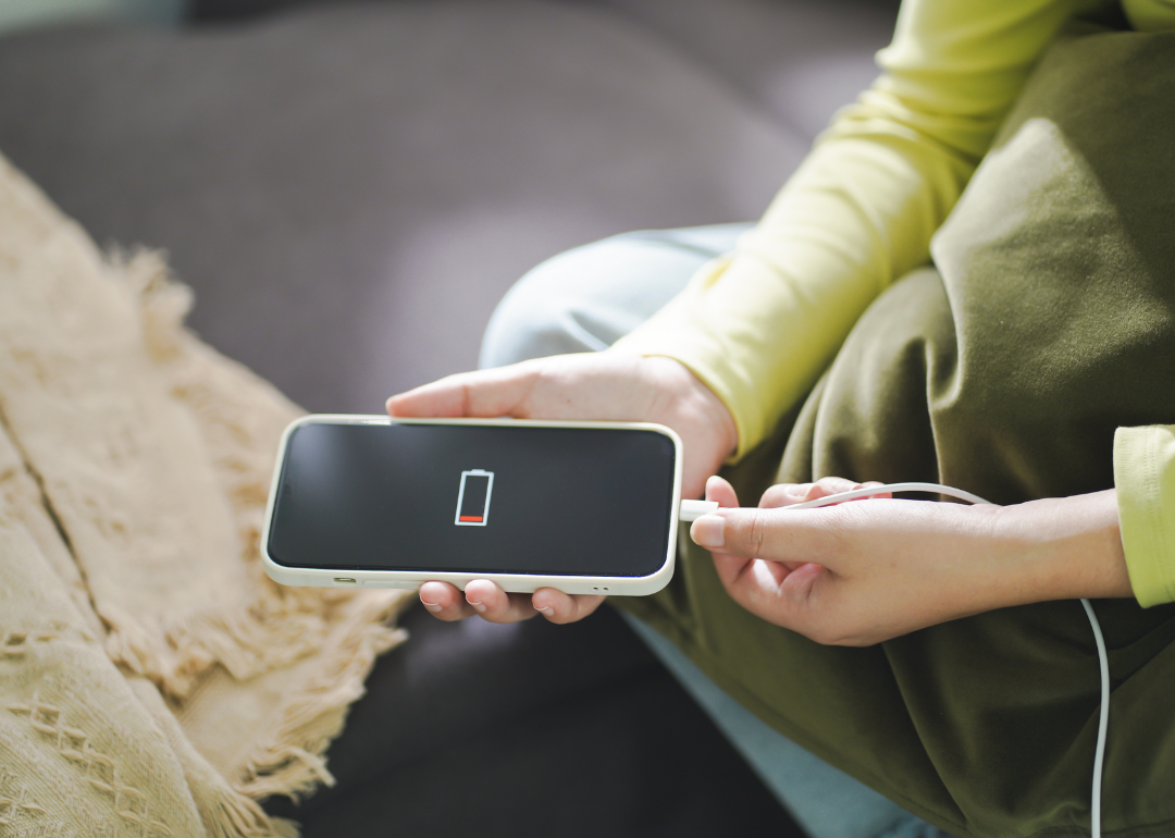 Person's hands plugging a low battery phone into a charger