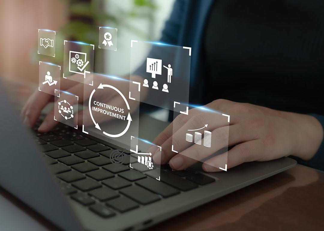 Continuous improvement concept illustrated by data icons superimposed over person typing on keyboard.