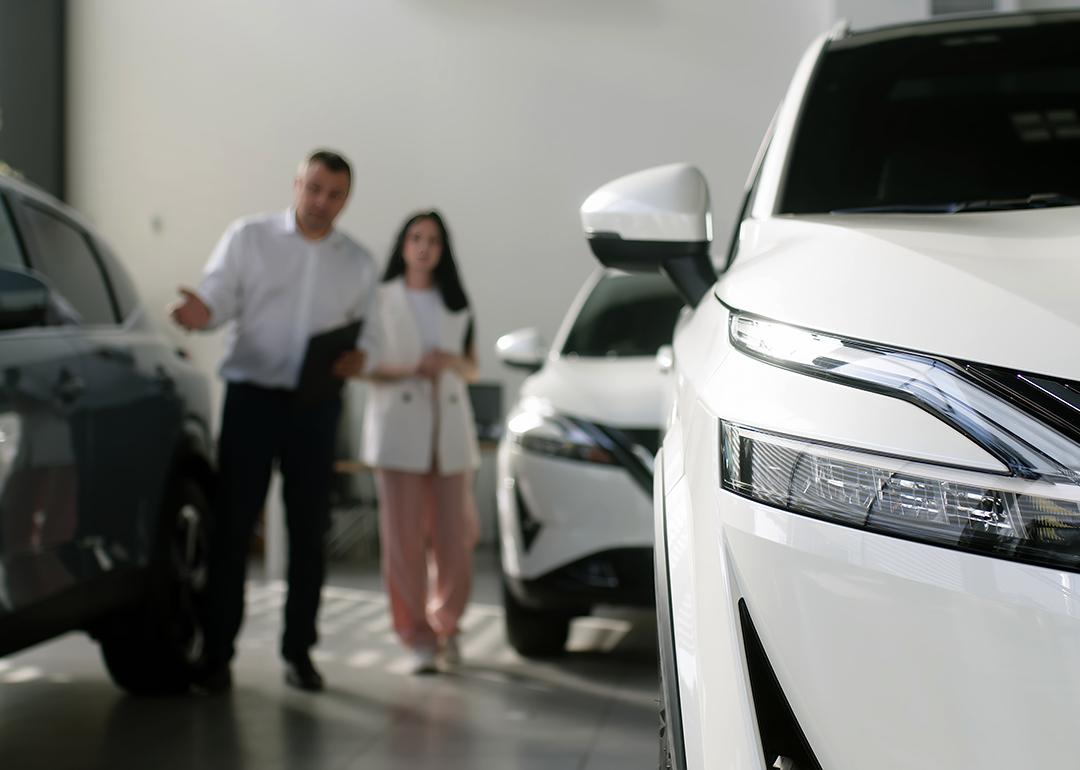 A car agent helps a woman look for a car to purchase.