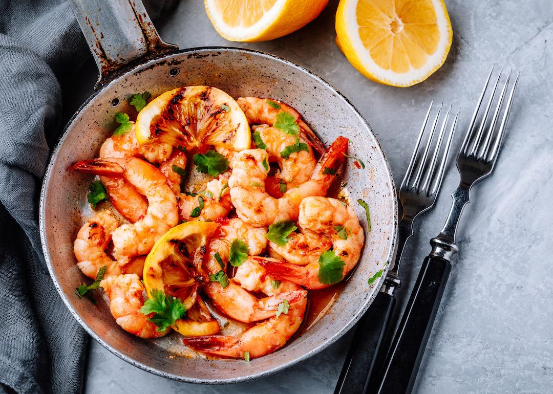 Garlic shrimp on frying pan with lemon and cilantro.