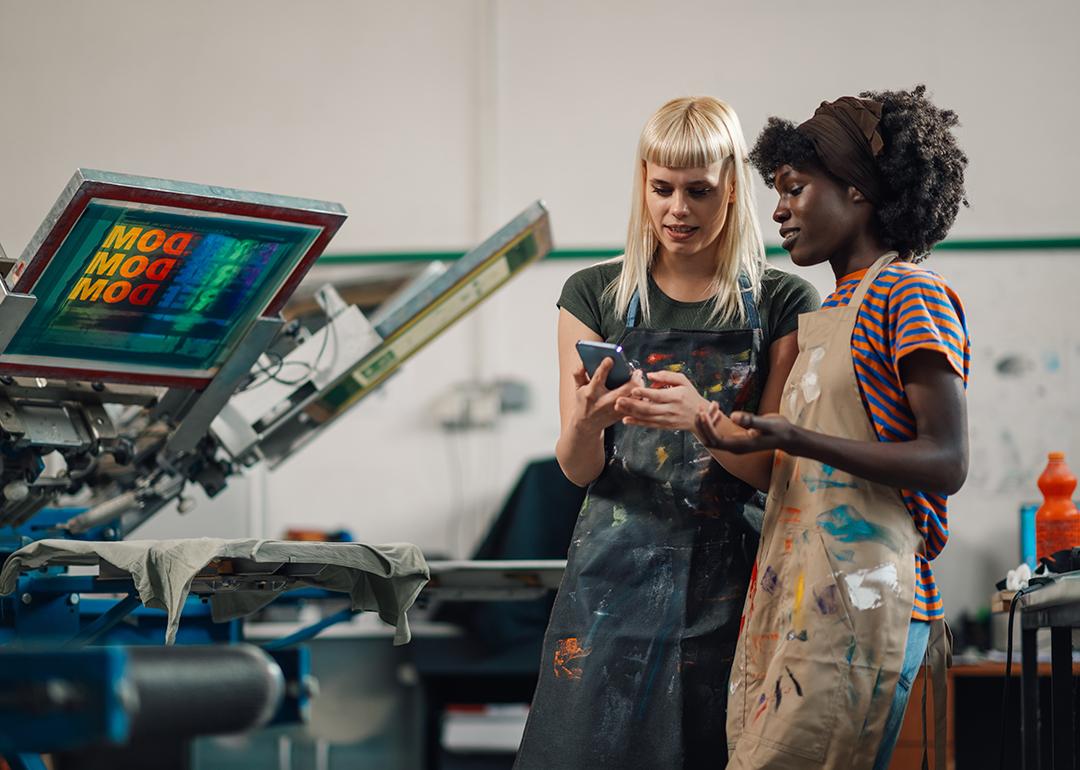 A shirt printing business and its workers looking at information in a phone.