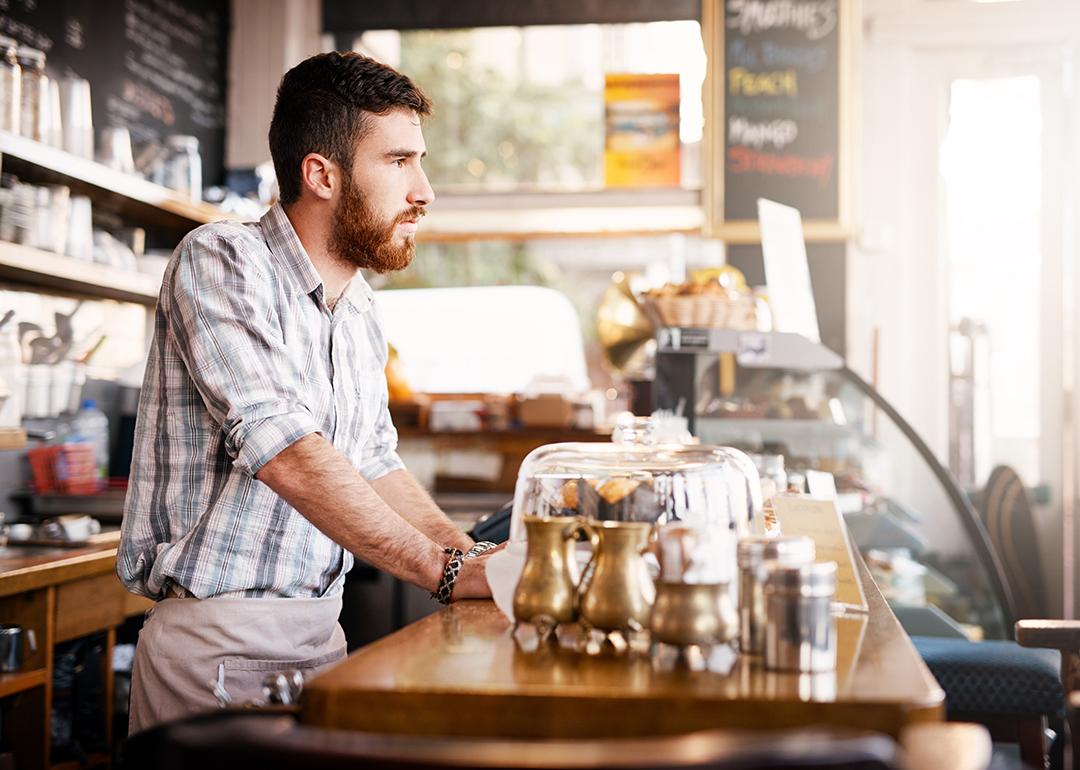 Small cafe owner looking at the outside of the cafe waiting for customers.