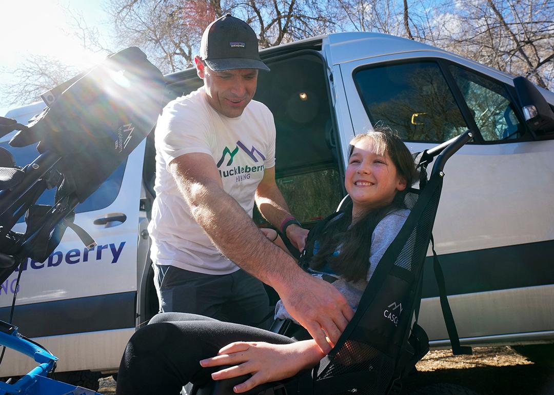 LJ Wilde, owner of Huckleberry Hiking, straps his daughter Luci into the hiking cart that he designed.