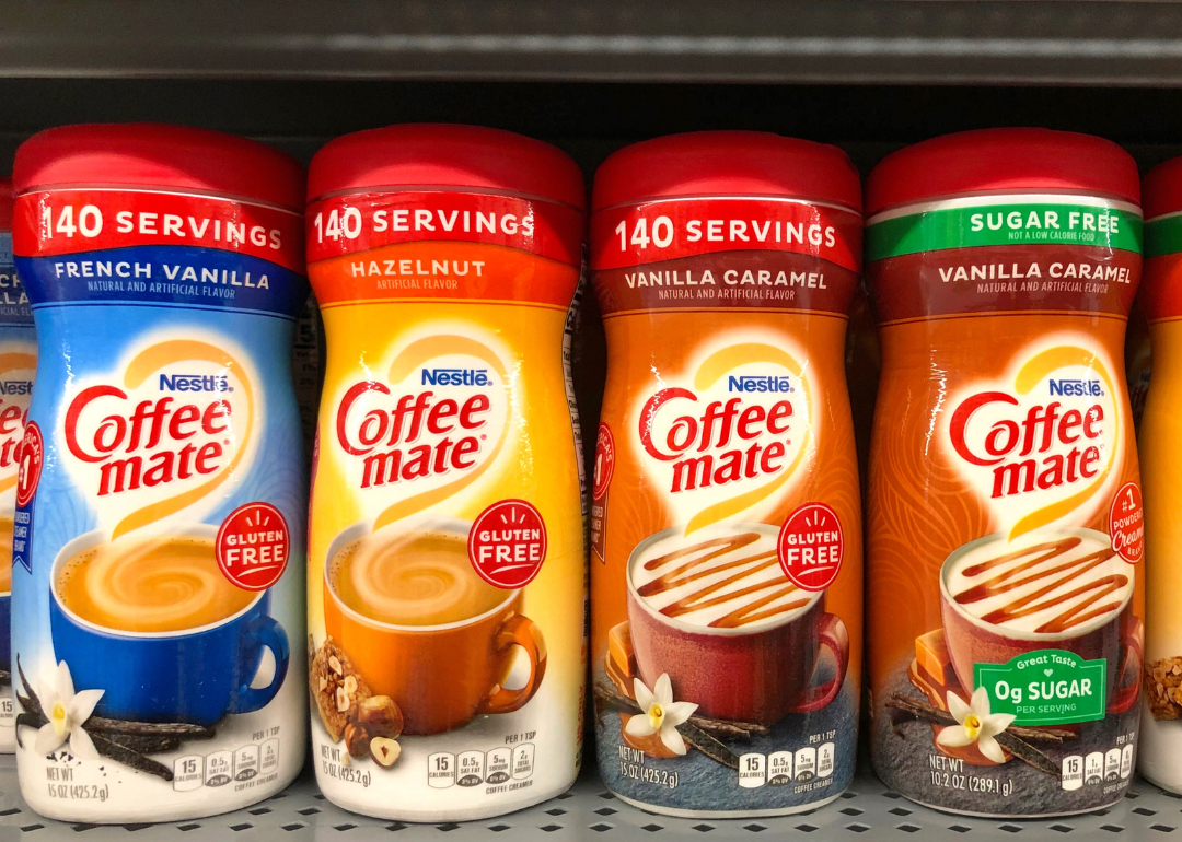 Grocery store shelf with containers of Nestle brand Coffee mate creamers in various flavors.
