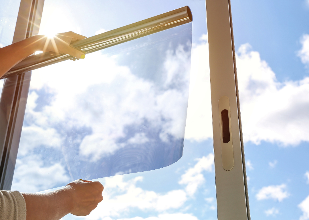 Person's hands applying UV filter film on glass window