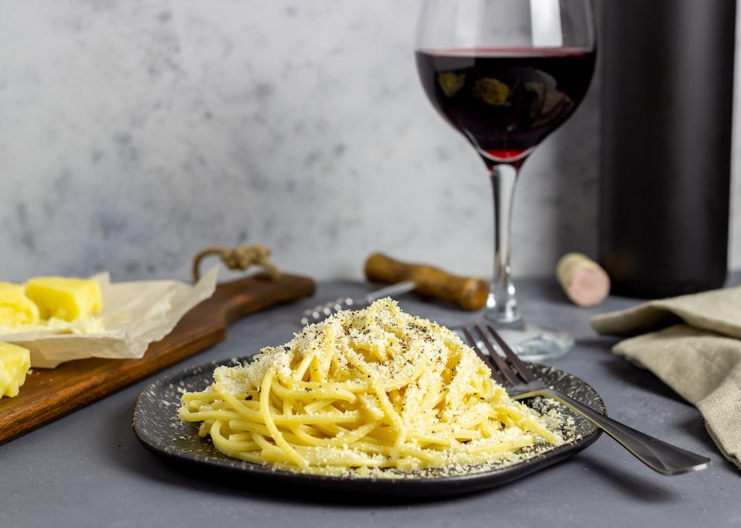 Roman pasta spaghetti cacio e pepe with black pepper, cheese, and wine.