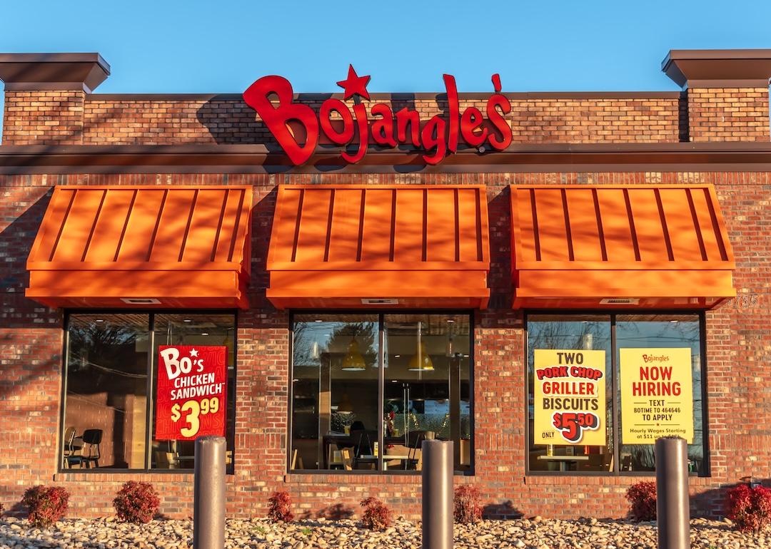 Exterior view of a Bojangles’ Famous Chicken ’n Biscuits restaurant at sunset, with brand signage against a clear blue sky.