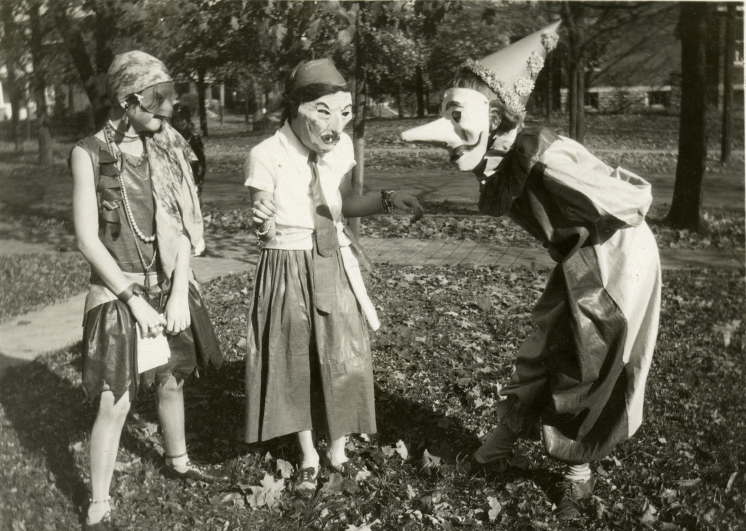 Three girls amuse each other with their masked costumes as they prepare for Halloween festivities in the College Hill neighborhood of Cincinnati, Ohio, 1929.