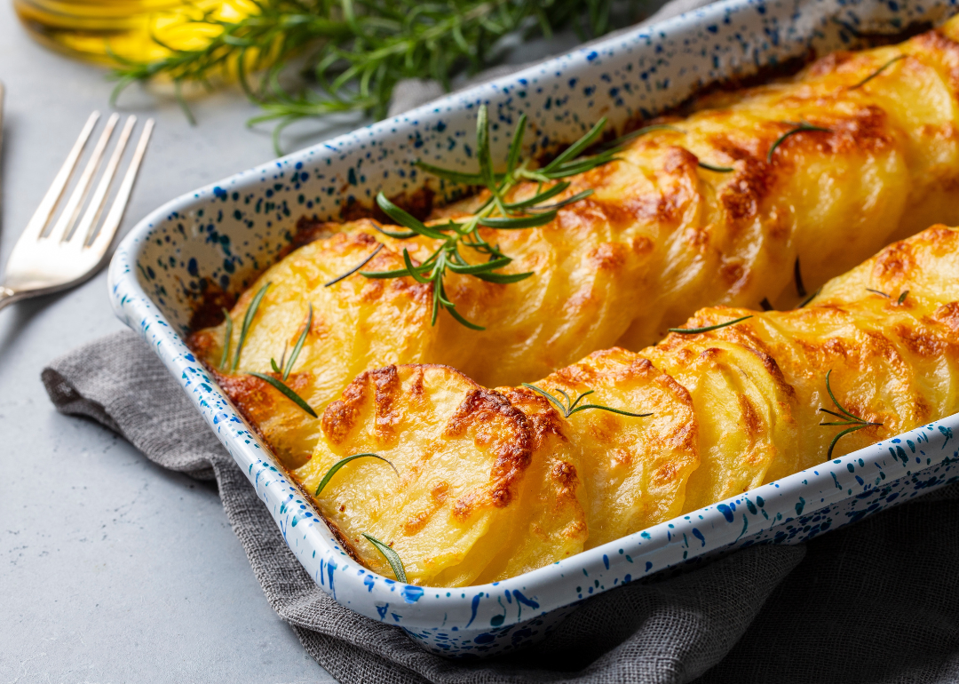 Potato gratin topped with rosemary in a baking dish