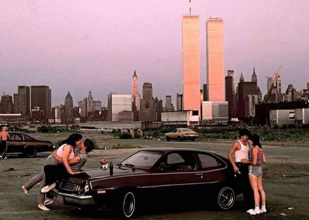 Couples hanging out on a car in New Jersey with Manhattan behind them