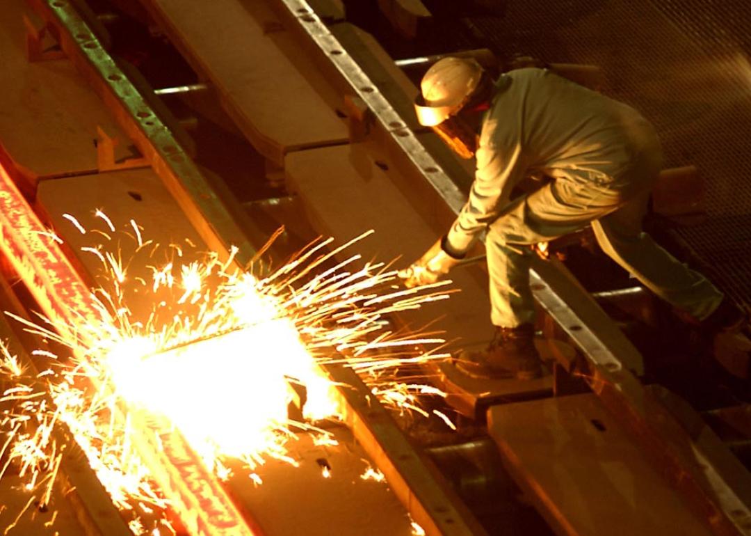 A worker cuts through a glowing 2,000 degrees Fahrenheit "billet" at the TAMCO steel mini mill