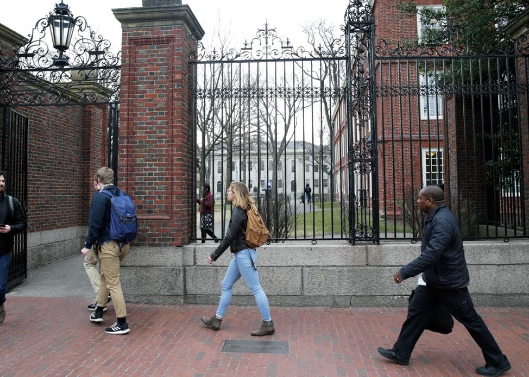 People walk through Harvard University's campus with a box in Cambridge, MA