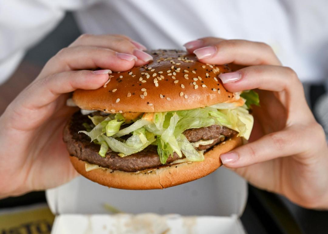 A photo of a woman holding a burger with two hands