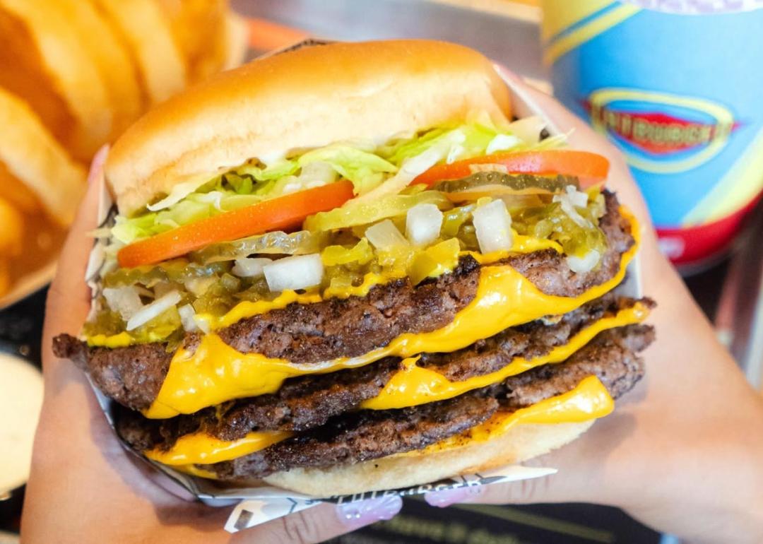 Hand holding a massive cheeseburger from Fatburger