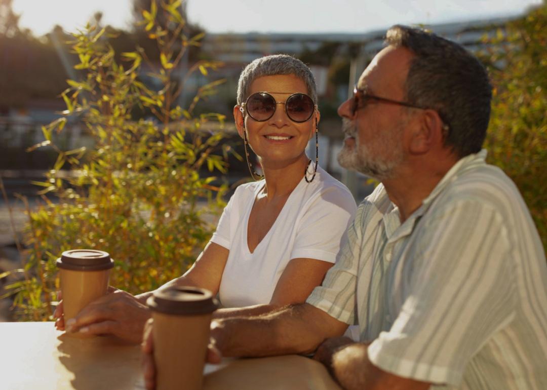 An older couple sitting outdoors at the table in warm sunlight.