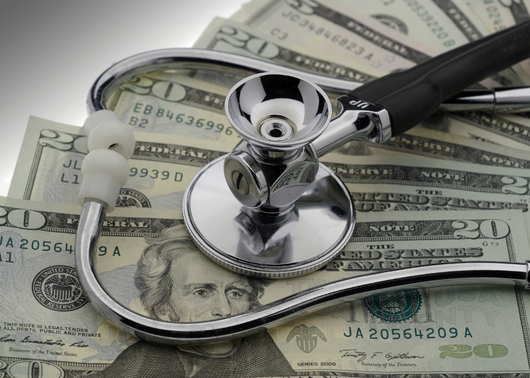 A stethoscope sitting on top of a pile of $20 bills. 