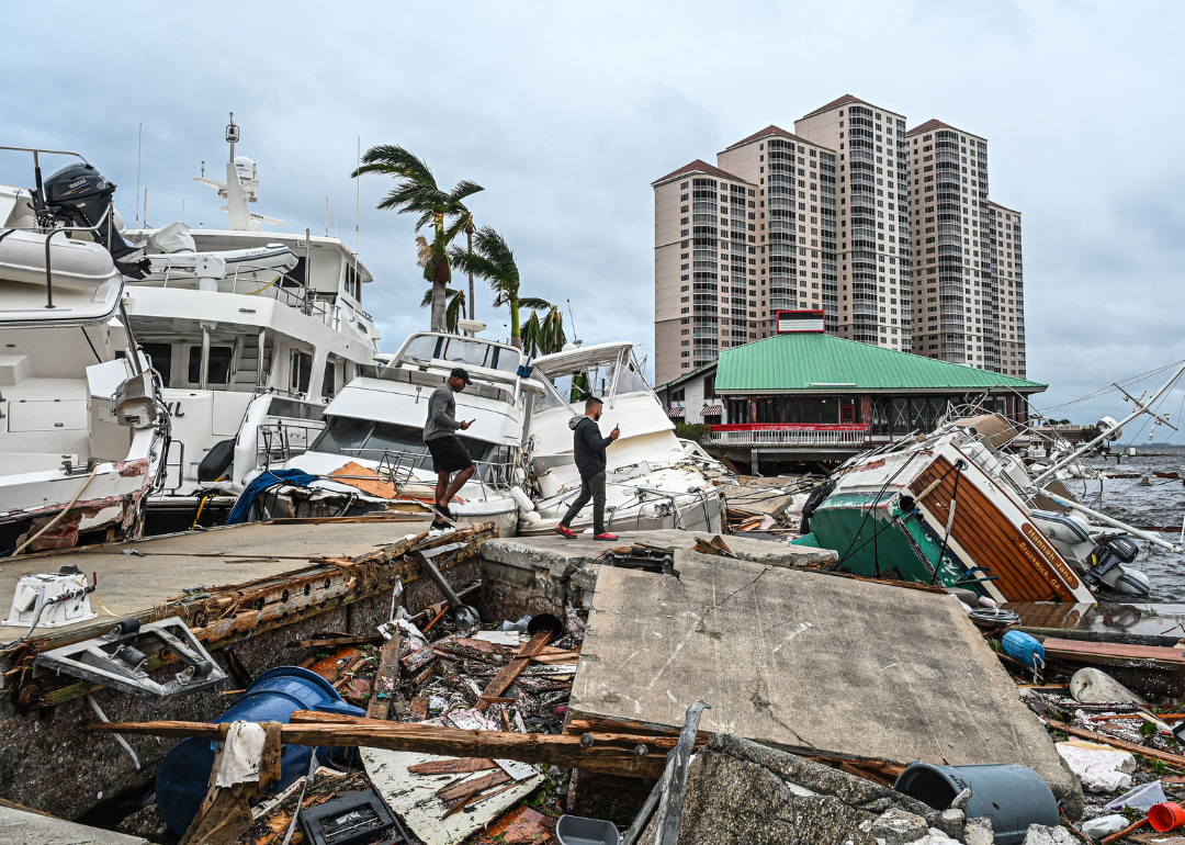 Image shows post-storm debris including toppled homes and boats
