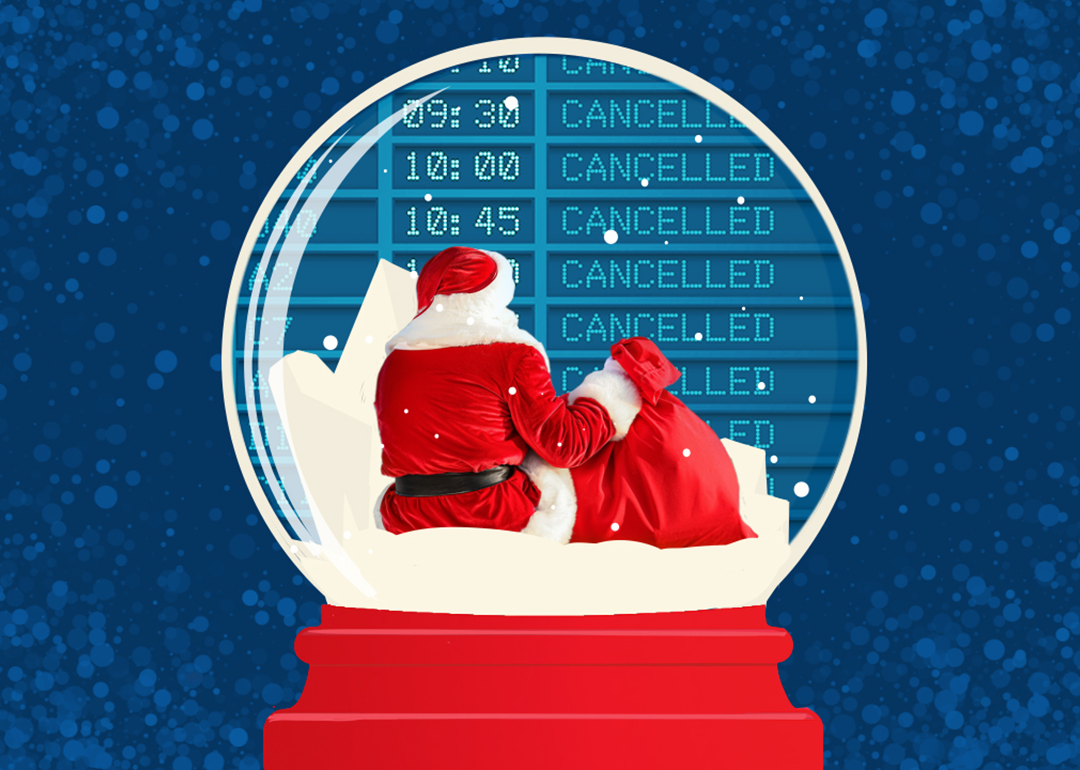 Santa sitting in front of a cancelled flight board inside a snow globe.