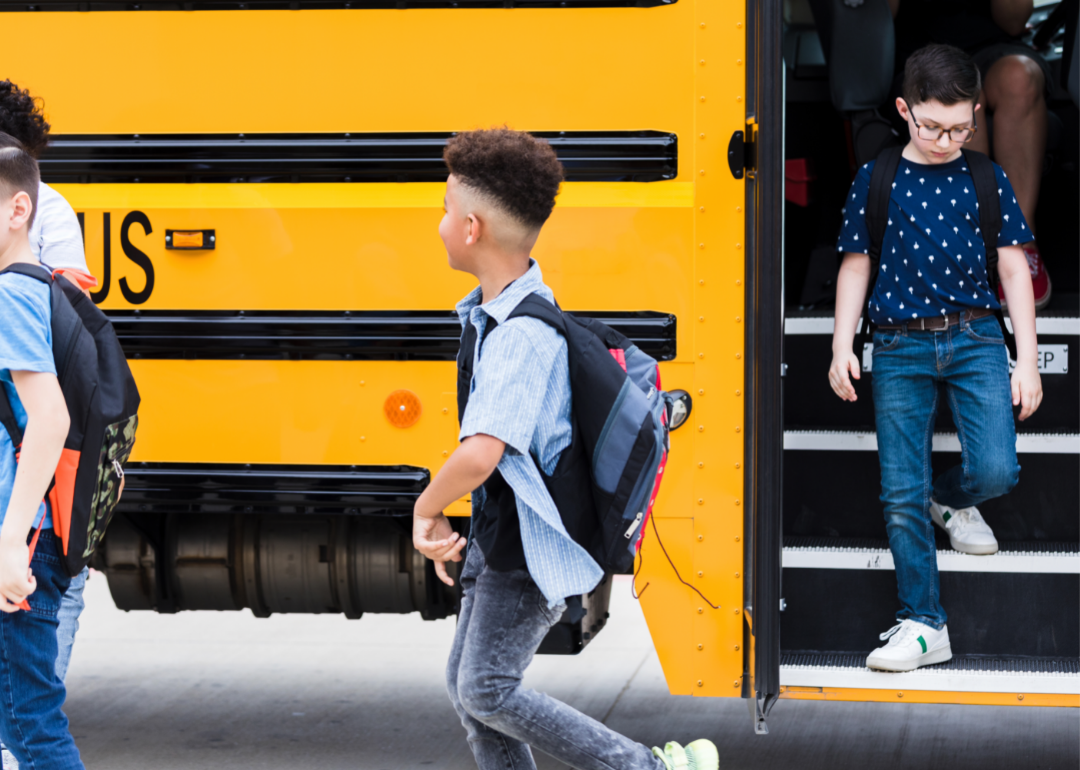 Young children exit a school bus. 