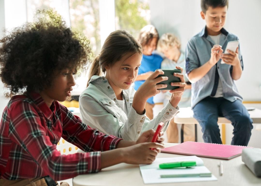 Kids looking at phones in a classroom.