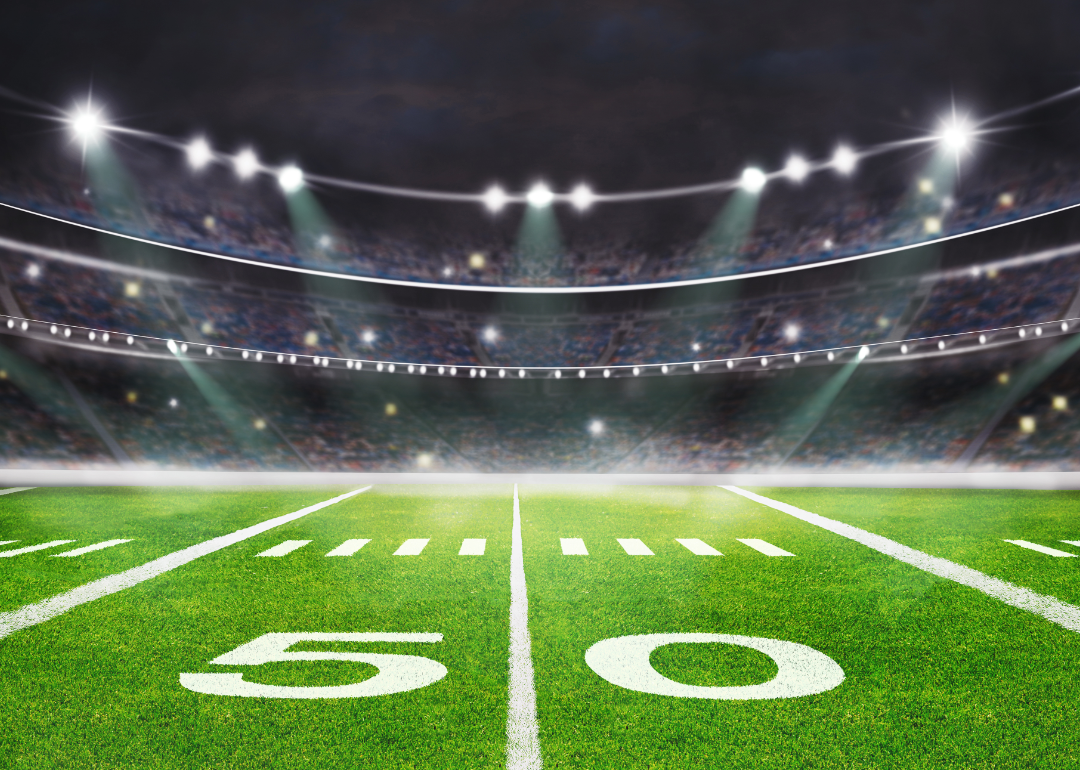 Spotlights shine on the 50 yard line of a football stadium