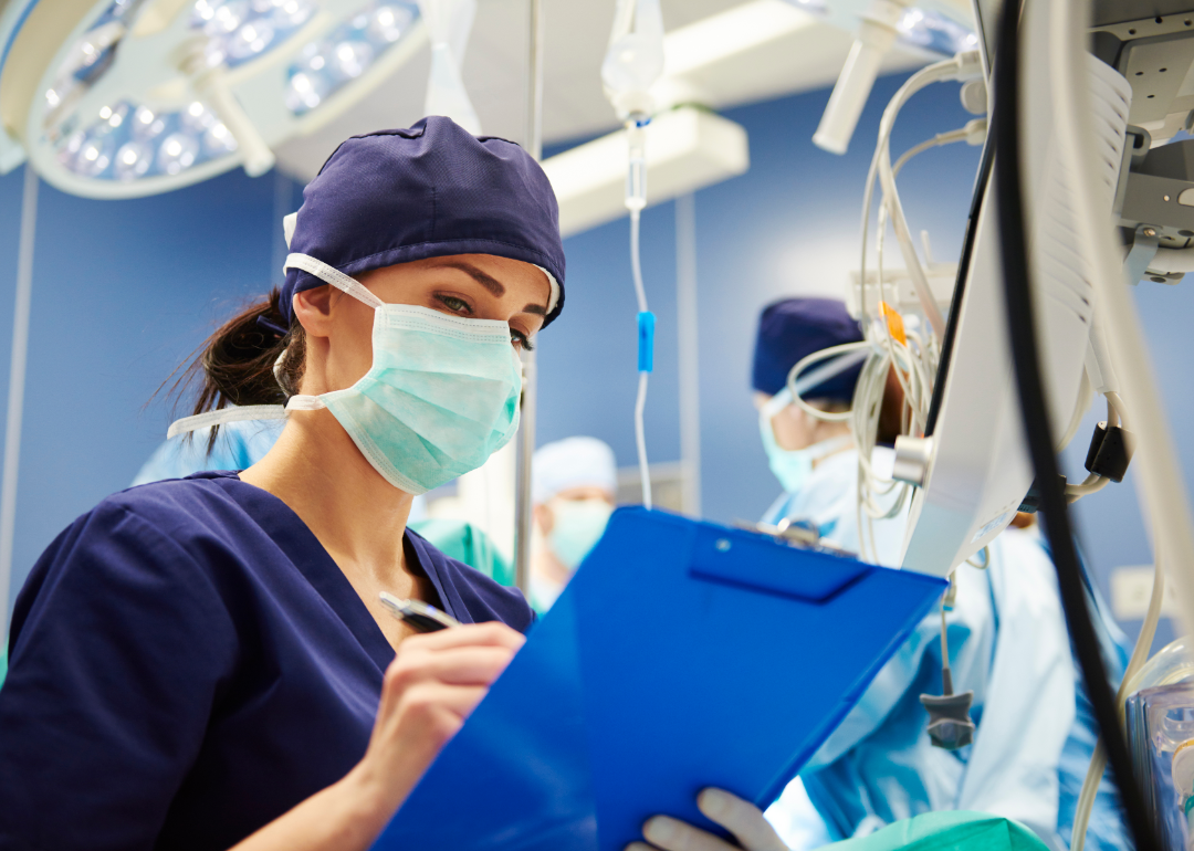 A medical technician takes notes in an operating room.