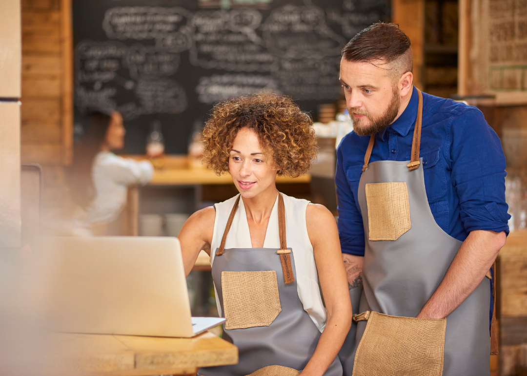 Small business owners using laptop in restaurant.