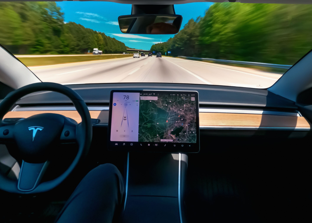 An interior view of a Tesla driving down a highway.