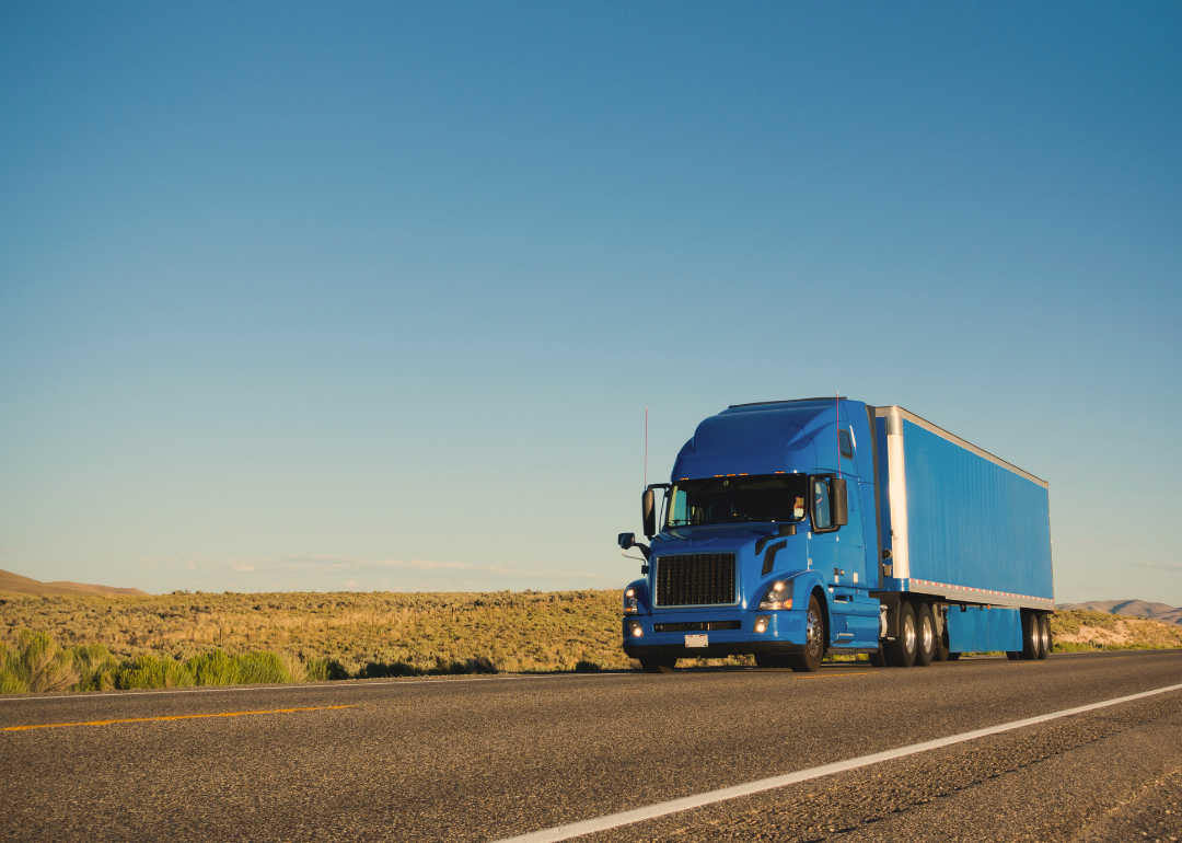 A large blue truck on a rural road. 