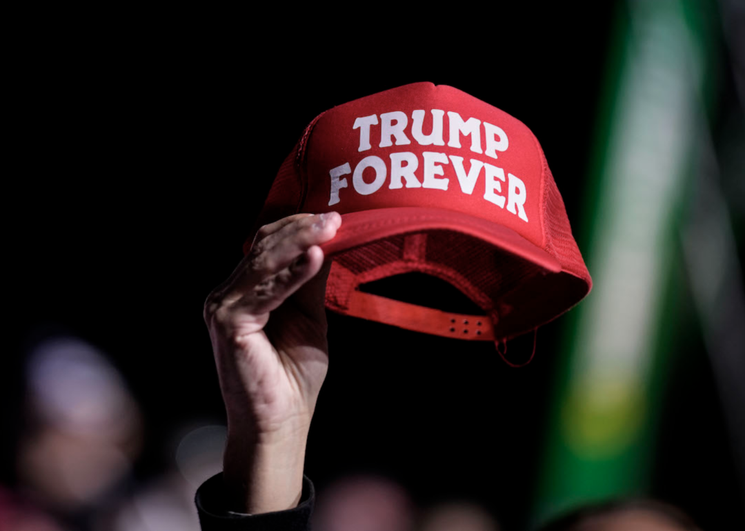 A supporter holds a Trump Forever hat in the air.