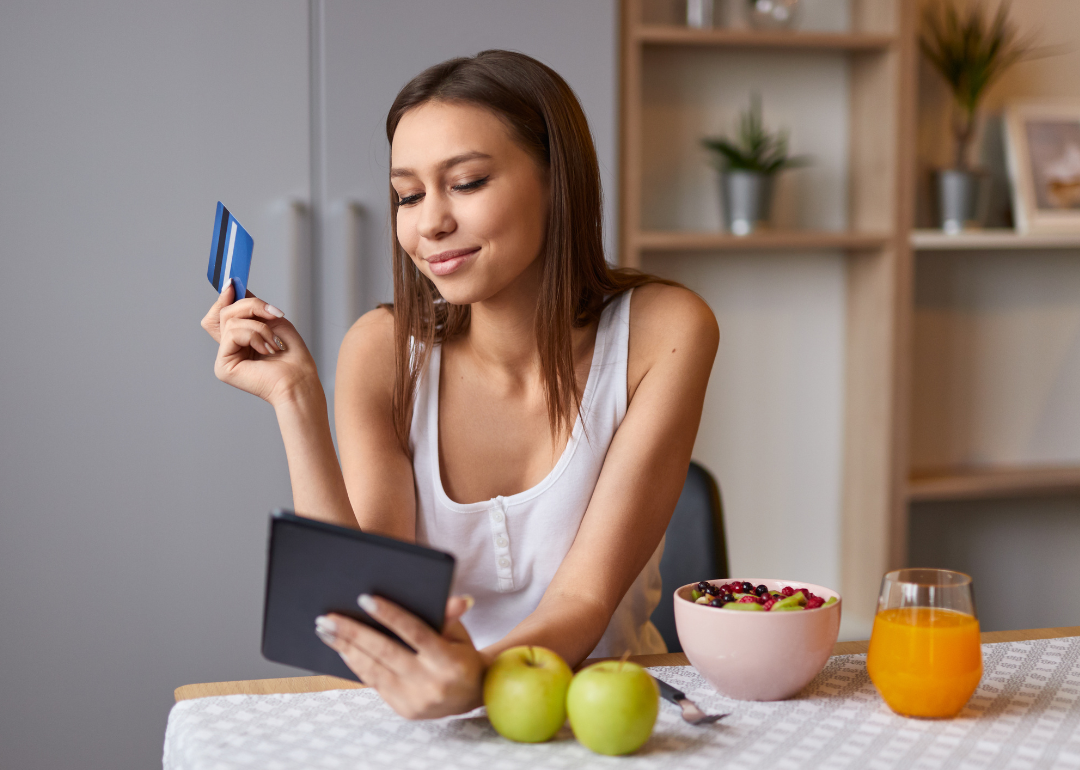 A happy woman shopping online during breakfast.