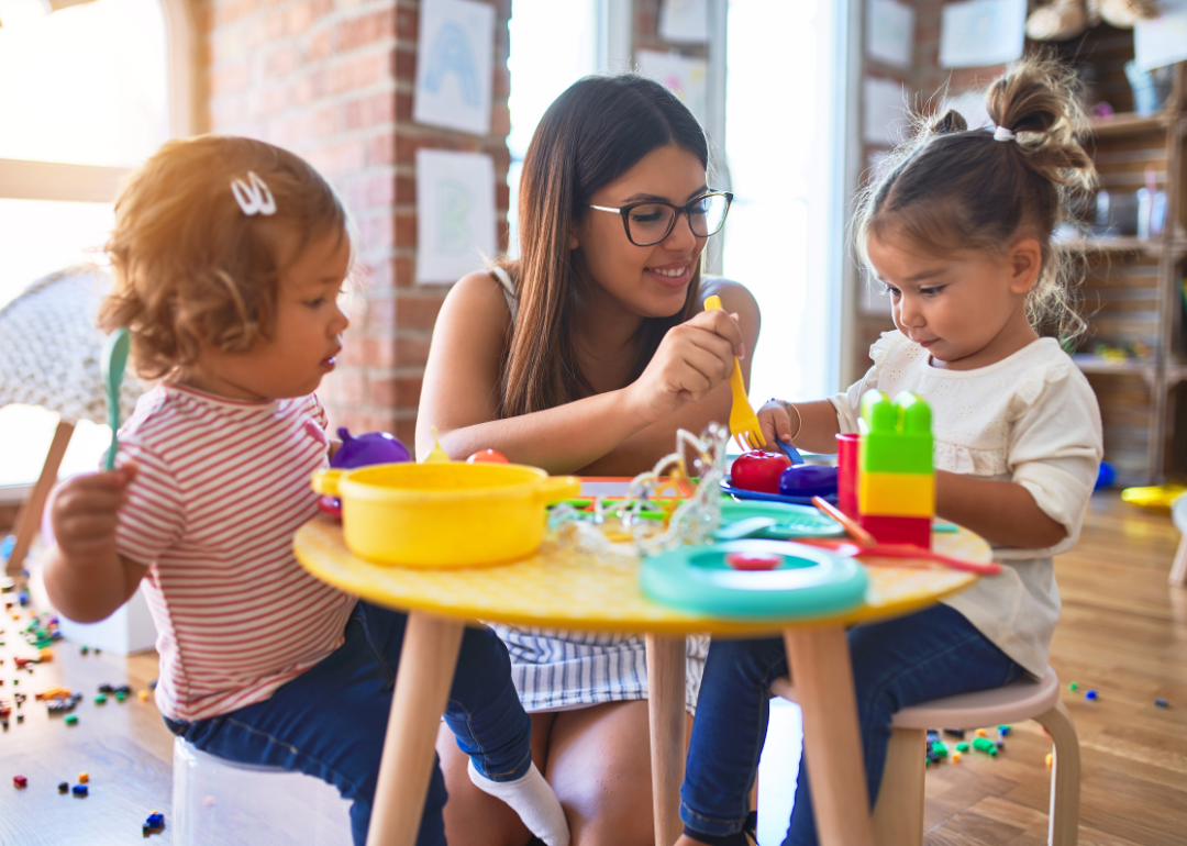 A preschool teacher playing with two toddlers