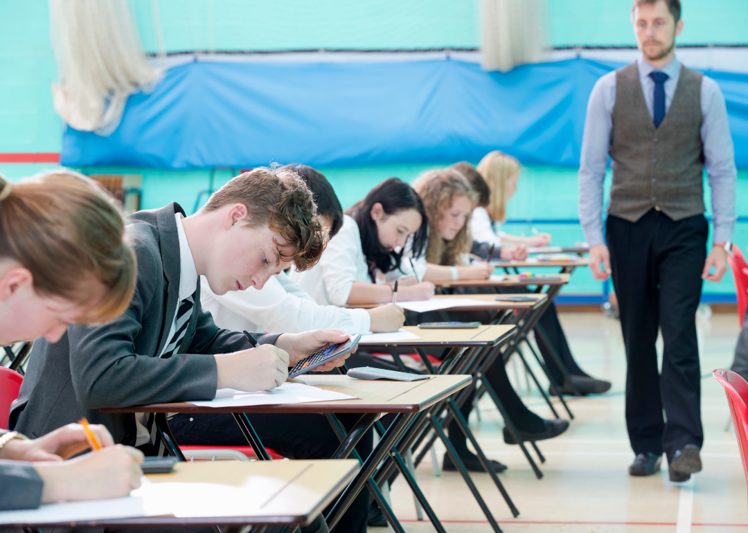 A teacher supervising students as they take an exam.