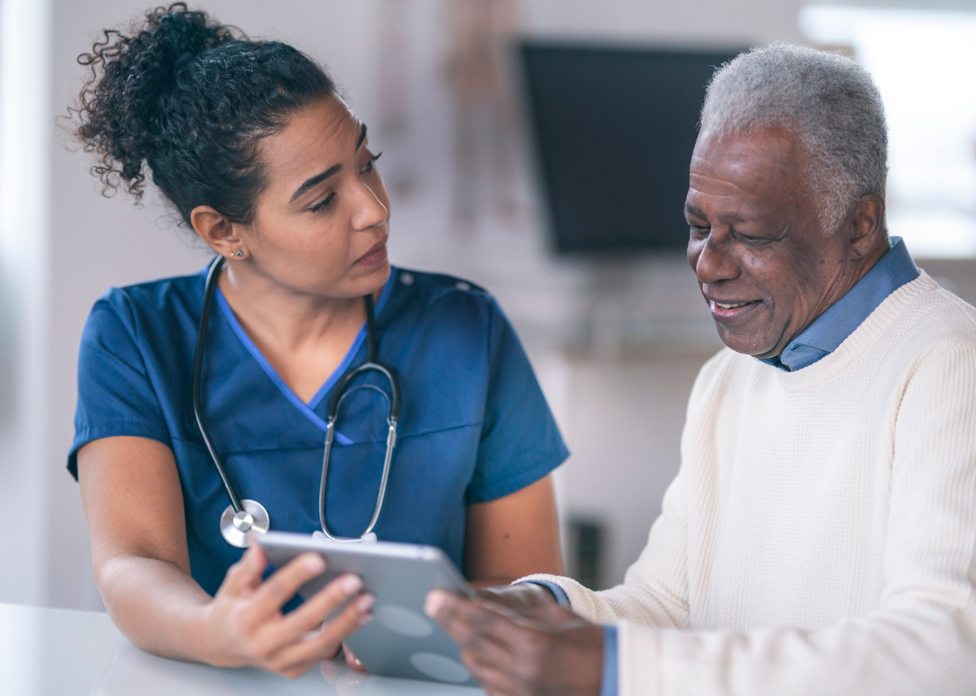 A nurse consulting a senior patient using an iPad.
