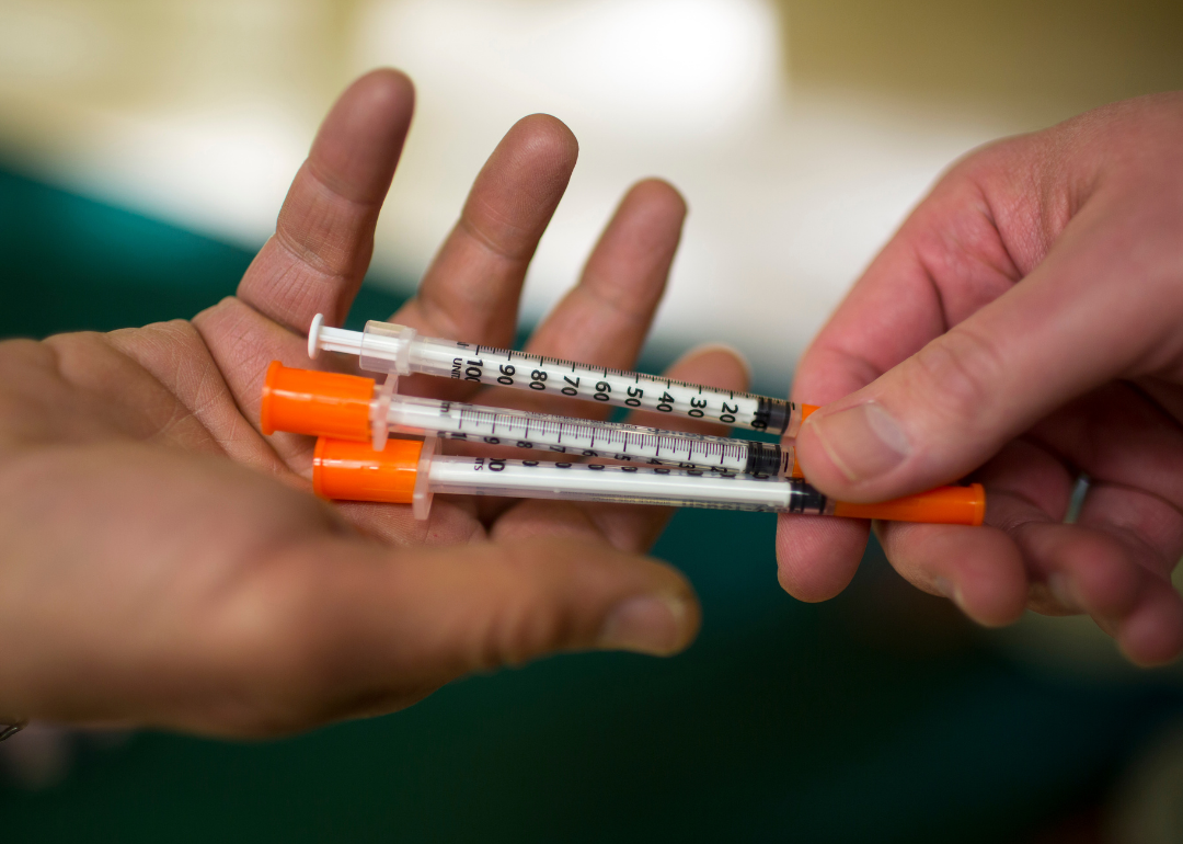 One person handing another three syringes at Howard Center's needle exchange program in Burlington, Vermont